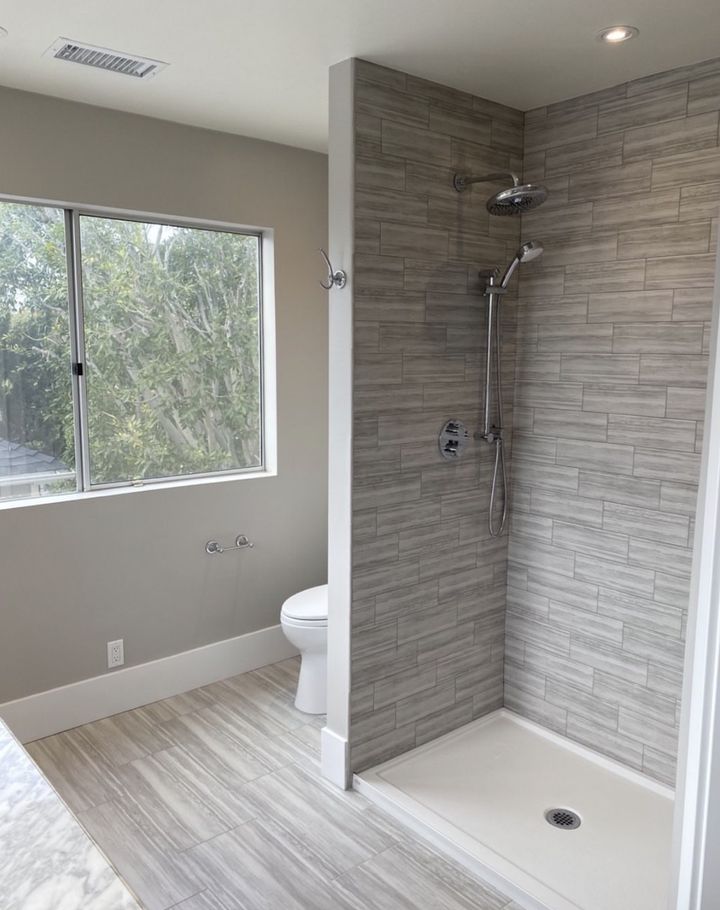 Primary bathroom with walk-in shower, tiled walls and floor, and a large window